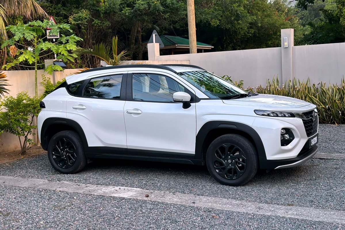 A white Suzuki Fronx parked on Mahé with jungle behind